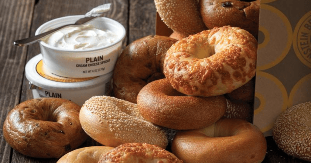 einstein bagels overflowing from an Einstein bagel box with 2 tubs of cream cheese and a knife